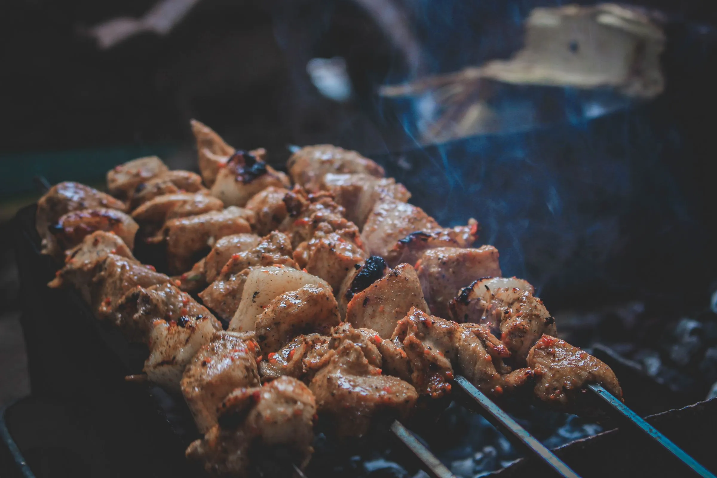 Lamb skewers cooking over hot coals.